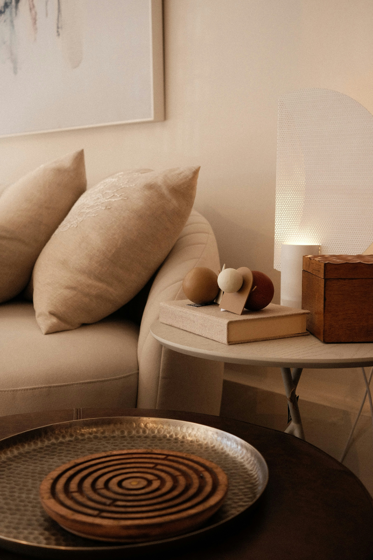 A warm, softly lit interior with linen cushions, a lamp and a hammered brass tray